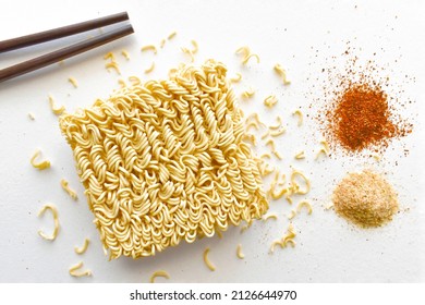 Instant noodles with seasonings on the table.  Uncooked noodles with dried red chilli flakes and ingredients on white.  Flat lay top view food photography.  Food from above concept. - Shutterstock ID 2126644970