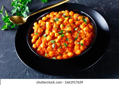 Instant Pot Indian Chana Masala Or Chickpea Curry With Spices, Tomato Sauce, Bay Leaf,  Sprinkled With Parsley On A Black Plate, On A Dark Concrete Background, Horizontal Orientation, Close-up