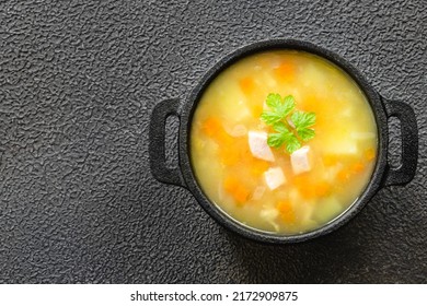 Instant pot potato bacon split pea soup in cast iron pot on dark background. Top view, copy space, flat lay.