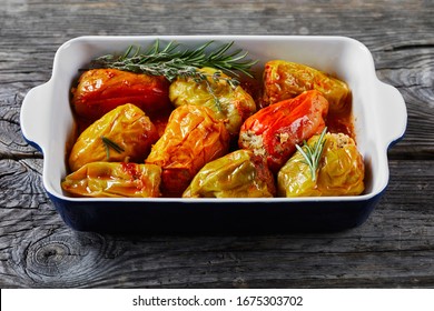 Instant pot sweet peppers stuffed with rice and minced meat: beef and pork with tomato sauce, rosemary, and thyme, cajun spices on a baking dish, on a wooden background, close-up