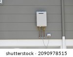 Instantaneous gas hot water heater on the side of a house 