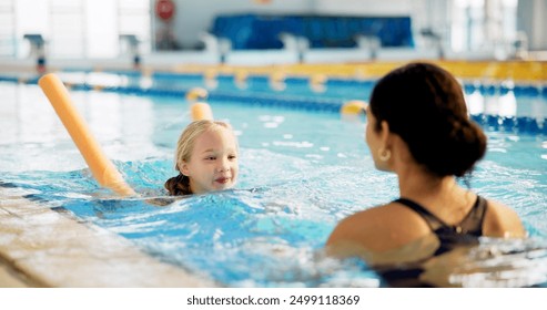 Instructor, active and girl in pool, swimming and woman with smile, proud and helping child in water. Lesson, happy and learning with teacher in school for training of kid, sports and teaching - Powered by Shutterstock