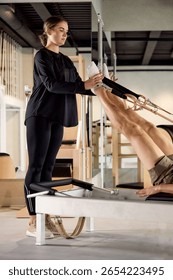 Instructor assisting client during Pilates workout using reformer equipment