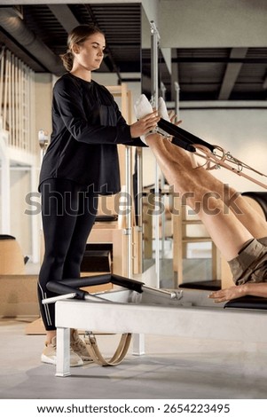 Instructor assisting client during Pilates workout using reformer equipment