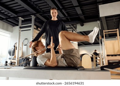 Instructor Assisting Client With Pilates Exercise on Reforming Machine