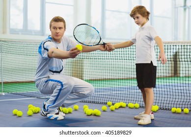 Instructor or coach teaching child how to play tennis on a court indoor - Powered by Shutterstock