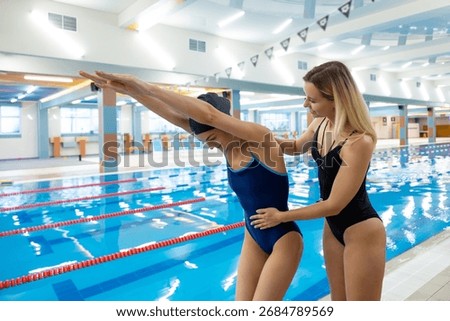 Instructor correcting swimmer technique before dive at poolside