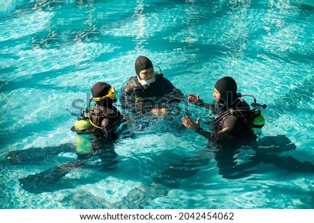 Instructor and divers in aqualungs, dive course