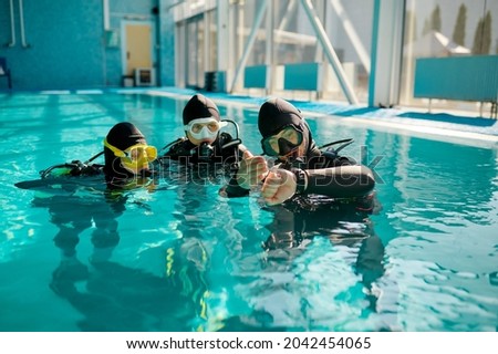 Instructor and divers in aqualungs, dive lesson