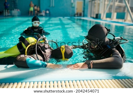 Instructor and divers in aqualungs, diving school