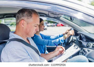 Instructor of driving school giving exam while sitting in car. Student driver taking driving test. Driving instructor and woman student in examination car