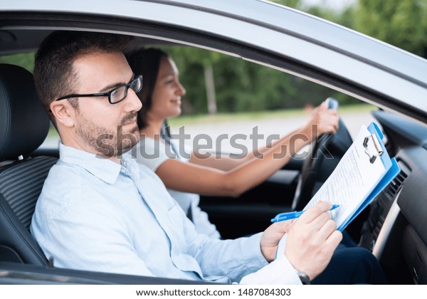 Instructor of driving school giving exam while\
sitting in car