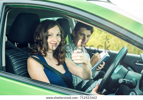 Instructor and Female student\
driving showing thumb up. The woman passed the exam in driving\
school.