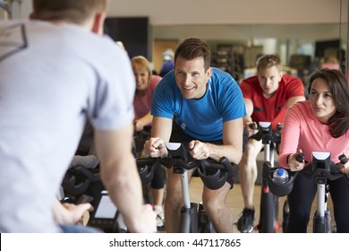 Instructor In Foreground With Spinning Class At A Gym