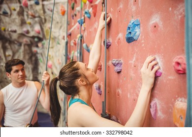 Instructor guiding woman on rock climbing wall at the gym - Powered by Shutterstock