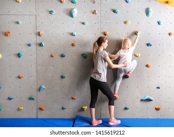 Instructor helping little girl to climb wall in gym - Powered by Shutterstock