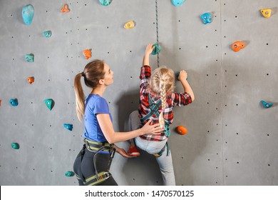 Instructor helping little girl to climb wall in gym - Powered by Shutterstock