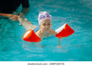 
Instructor Helping Little Girl Teaching her to Swim. Swimming coach instructing the little kid to use her hands 
 - Powered by Shutterstock