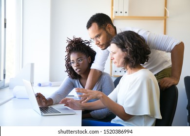 Instructor Helping New Employees With Corporate Software. Diverse Man And Women Sitting And Standing At Desk, Using Computer, Talking. Training Concept