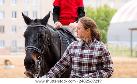 Instructor leads horse while young rider focuses during a riding lesson. Riding school