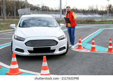 Instructor Near Car With His Student During Exam At Driving School Test Track