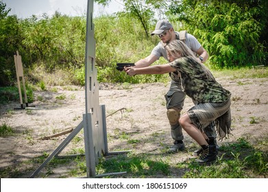 Instructor on shooting range teaches his female student tactical gun shooting behind and around cover or barricade. Firearm shooting and weapons training