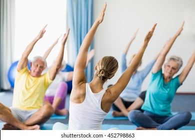 Instructor performing yoga with seniors during sports class - Powered by Shutterstock