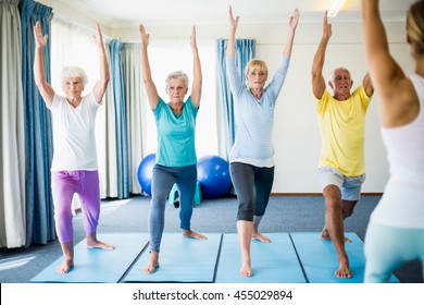 Instructor Performing Yoga With Seniors During Sports Class