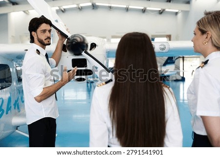 Instructor pilot teaching aviation students about an airplane propeller during ground training in a hangar