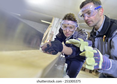 Instructor showing trainee how to use sawing machine