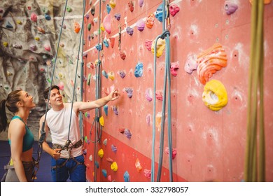 Instructor Showing Woman Rock Climbing Wall At The Gym