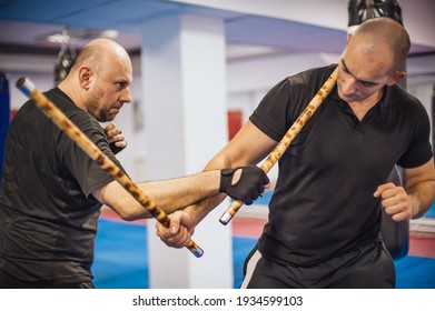 Instructor and student practice filipino escrima stick fighting technique. Martial arts demonstration