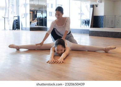 Instructor supporting a ballet dancer stretching her legs - Powered by Shutterstock