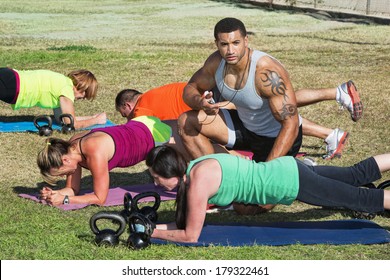 Instructor With Tattoo Helping Bootcamp Fitness Students