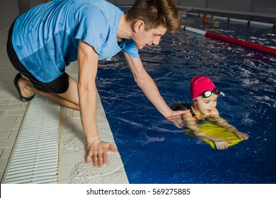 Instructor Teaches The Child To Swim In The Pool