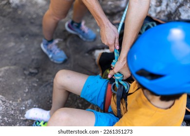 The instructor teaches the child to use climbing equipment, The boy is preparing to climb the rock.  - Powered by Shutterstock