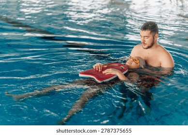 Instructor teaching a boy back floating in an indoor swimming pool, helping him learn water safety during a swimming class