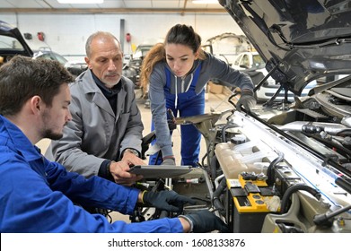 Instructor with trainees working on car engine 
