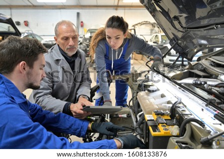 Instructor with trainees working on car engine 