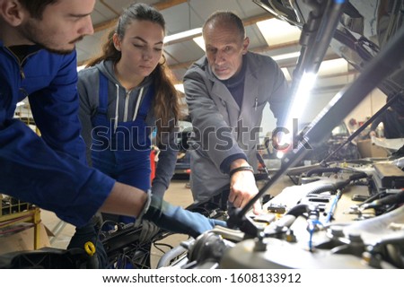 Instructor with trainees working on car engine 