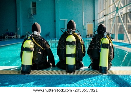 Instructor and two divers in suits, back view