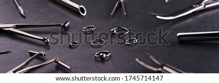 instrument for piercing, clips lying next to with earrings on a black background