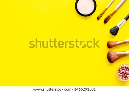 Instruments for make up with brushes, blusher and powder on yellow background top view mock up