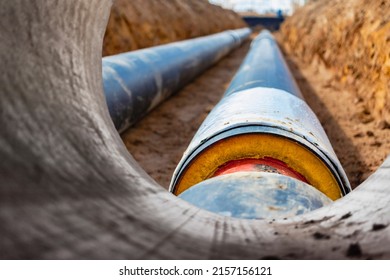 Insulated pipe. Large metal pipes with a plastic sheath laid in a trench. Modern pipeline for supplying hot water and heating to a residential area - Shutterstock ID 2157156121