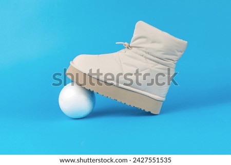 Insulated women's shoe and a white balloon on a blue background. Women's shoes for cold weather.