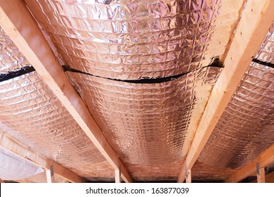 Insulating of attic with fiberglass cold barrier and reflective heat barrier used as baffle between the attic joists to increase the ventilation to reduce humidification