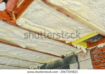 Insulation of the ceiling in the house with polyurethane foam. Insulating foam between wooden beams