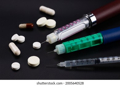 Insulin Syringe Pens, Insulin Syringe, Tablets And Capsules For The Treatment Of Diabetes On A Black Background. Close-up.