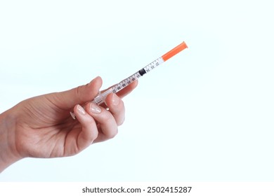 Insulin syringe. A woman's hand holds a syringe on a white background, close-up. Insulin syringe for diabetes. Diabetes treatment. Medicine and health concept - Powered by Shutterstock