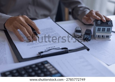 Insurance Advisor Pointing to Insurance Policy Document on Desk. Bundling Home and Auto Insurance Policy Planning Concept.